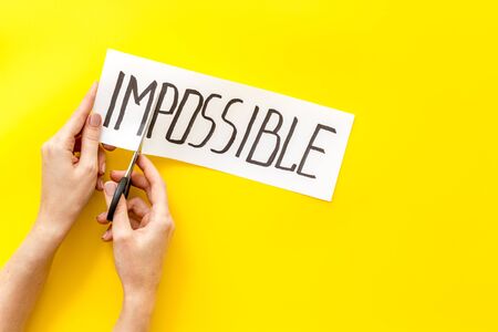 All is possible concept. Hands cut word impossible on yellow background.の写真素材
