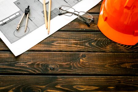 Construction concept. Helmet and blueprints on dark wooden background.の写真素材