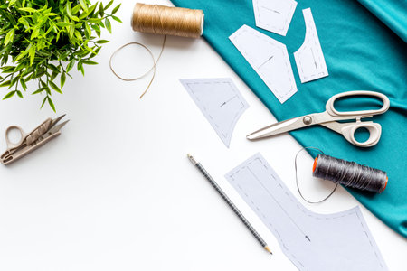 Sewing workshop. Textile, pattern, scissors, thread on white background top-down.