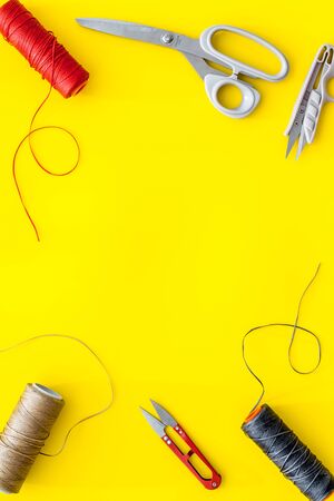 Tailor's work desk. Thread and sciccors on yellow background top-down.の写真素材