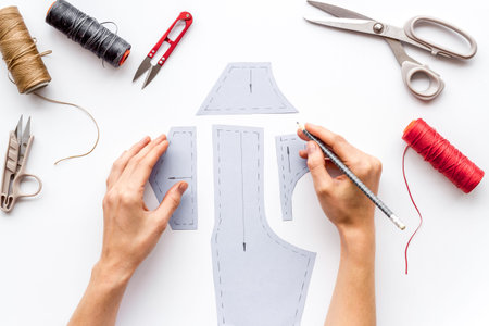 Tailor working. Women hands drawing patterns for clothes on white background top-down.