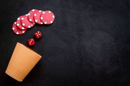 Poker hazard game concept. Chips, dices, cup for dice on black background top-down.の写真素材