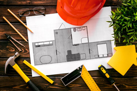 House building plan. Blueprints, instruments, helmet on dark wooden background top-down.