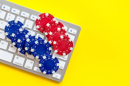 Gambling, online games. Chips near keyboard on yellow background top-downの写真素材