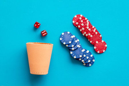Poker hazard game concept. Chips, dices, cup for dice on blue background top-down