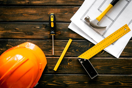 Construction concept. Helmet, instruments on dark wooden background top-down.