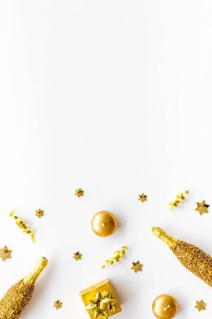 New Year background. Golden composition with champagne bottle and decorations on white desk top-down frame.の写真素材