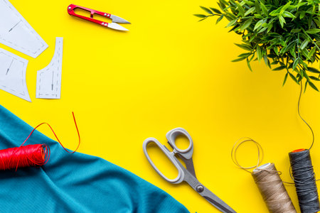 Sewing wokrshop. Textile, pattern, scissors, thread on yellow background top-down.