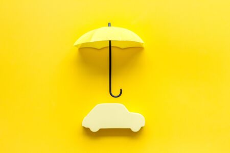 Automobile toy under umbrella on yellow background top-down copy spaceの写真素材