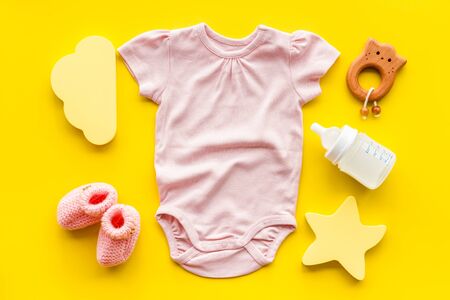 Pink bodysuit for baby girl near childrens things on yellow background top-downの写真素材