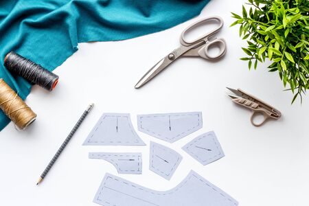 Clothes designer work desk. Pattern, scissors, thread, textile on white background top-downの写真素材