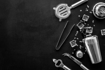 Bar utensil, tools - shaker, strainer - near ice cubes on black background top-down.の写真素材