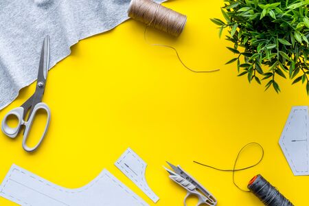 Sewing workshop. Textile, pattern, scissors, thread on yellow background top-down.の写真素材