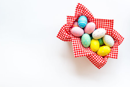 Easter eggs painted in basket on white desk top-down copy space