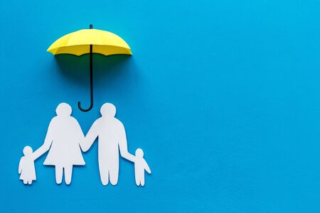 Health protection concept. Family cutout under umbrella on blue background top-down copy spaceの写真素材