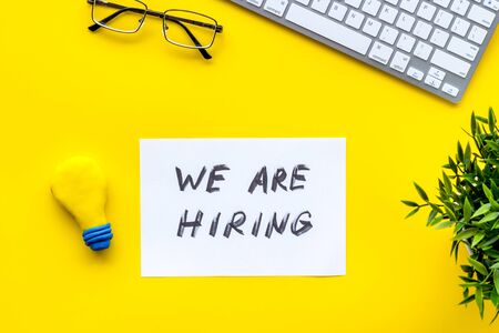 We are hiring. Text on yellow office desk top-down.の写真素材
