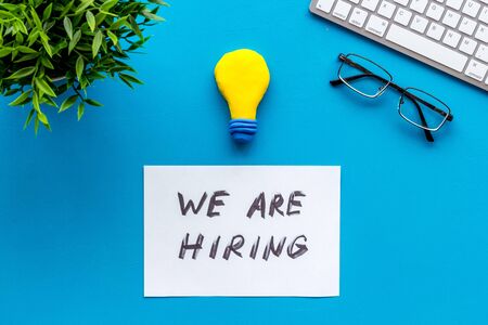 We are hiring. Text on blue office desk top-down copy spaceの写真素材