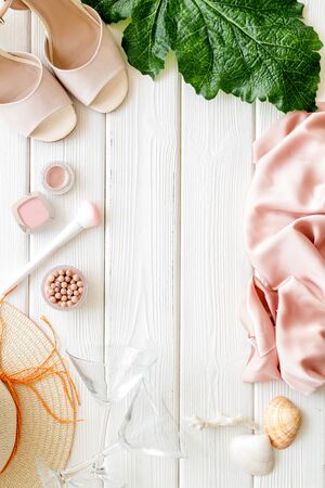 Female outfit. Clothes, shoes, cosmetics on white wooden background top-down frame copy spaceの写真素材