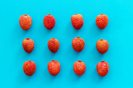 Lychee fruits pattern on blue background flat lay top-down