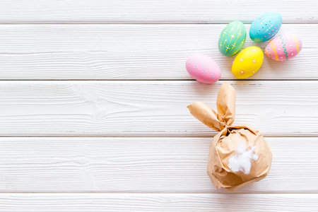 Easter symbols. Bunny and painted eggs on white wooden background top-down frame copy space