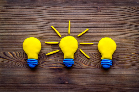 Creativity concept. Bulb icons on dark wooden background top-down