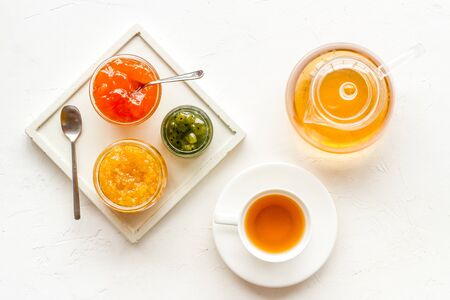 Fruit jam near tea on white kitchen desk.の写真素材