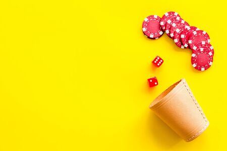 Poker hazard game concept. Chips, dices, cup for dice on yellow background top-down copy spaceの写真素材