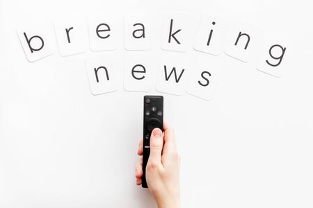 News concept. Breaking news. TV remote in hand on white background top-down copy spaceの写真素材