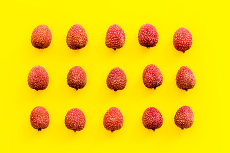 Lychee fruits pattern on yellow background flat lay top-down