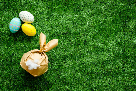 Easter symbols. Bunny and painted eggs on green grass background top-down.