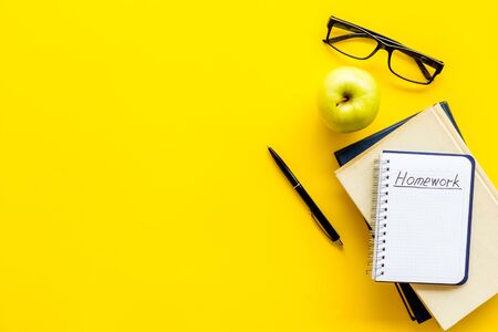 Books for homework on yellow student desk top-down copy space