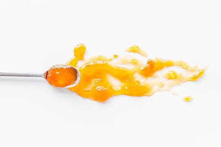 Fruit jam. Yellow dessert smashed by spoon on white deskの写真素材