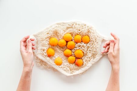 Eco shopping. Textile bag with fruits in hands on white background top-downの写真素材