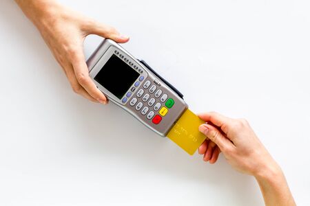 Payments in shops. Hand insert bank card in terminal on white background top-down copy space