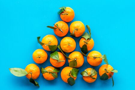 Tangerines with leaves - triangle shape - on blue background top-down.の写真素材