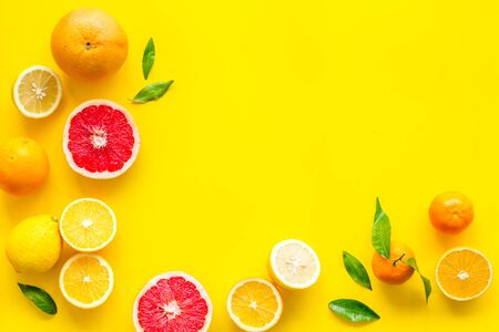 Fresh citrus frame. Oranges, tangerines, grapefruits, leaves on yellow background top-down.の写真素材
