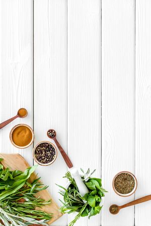 Making spices. Herbs in motar and dry flavorings on white wooden table top-down.の写真素材