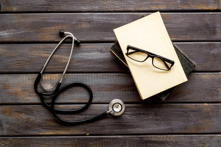 Medical books near stethoscope on dark wooden background top-downの写真素材