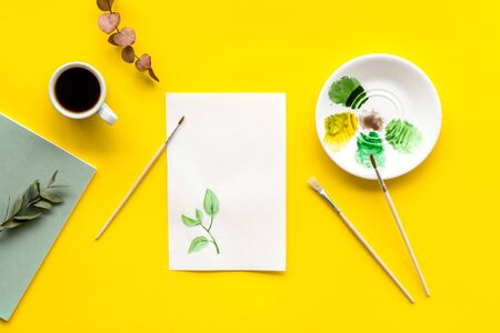 Drawing background with picture, paints, brushes on yellow table top-down.の写真素材