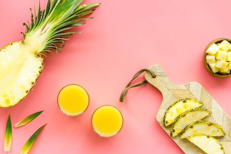 Pineapple juice on pink table with half of fruit top-down.の写真素材