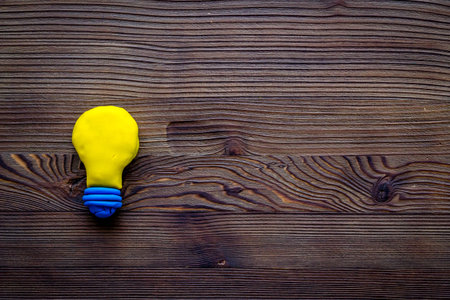 Invention concept. Bulb icon on dark wooden background top-down copy space