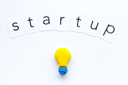 Startup concept with bulb icon on white background top-down.