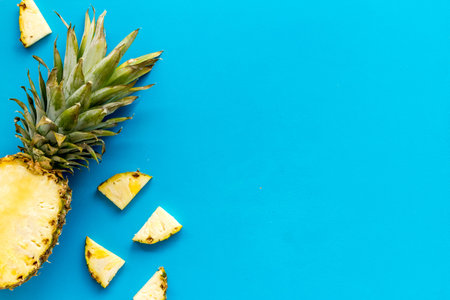 Pineapple - half of fruit and slices - on blue background top-down.
