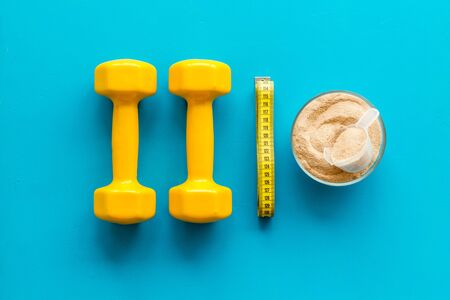Sport diet. Protein shake near dumbbells on blue background top-down flat layの写真素材