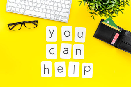 You can help text. Donation online concept with bank card and keyboard on yellow background top-down.の写真素材