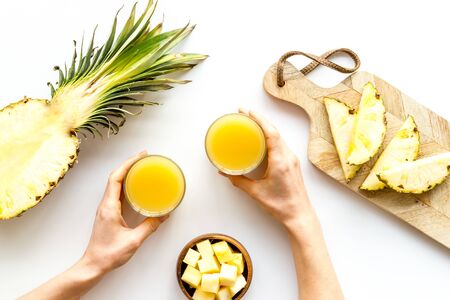 Pineapple juice in hands near sliced fruits on white background top-downの写真素材