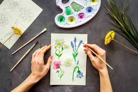 Painting. Female hands draw flowers on grey background top-down.の写真素材