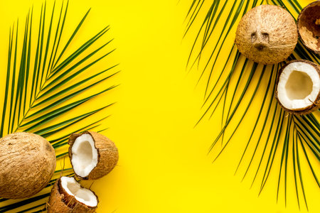 Exotic background with coconuts and palm leaves on yellow background top-down.