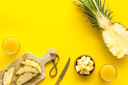 Make pineapple juice. Glasses near sliced fruits on yellow background top-down.の写真素材