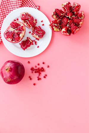 Juicy pomegranate with seeds on plate on pink table top-down.の写真素材